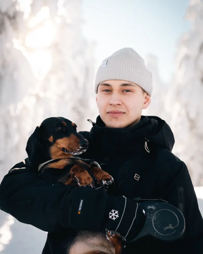 Milo koiransa kanssa lumisessa metsässä